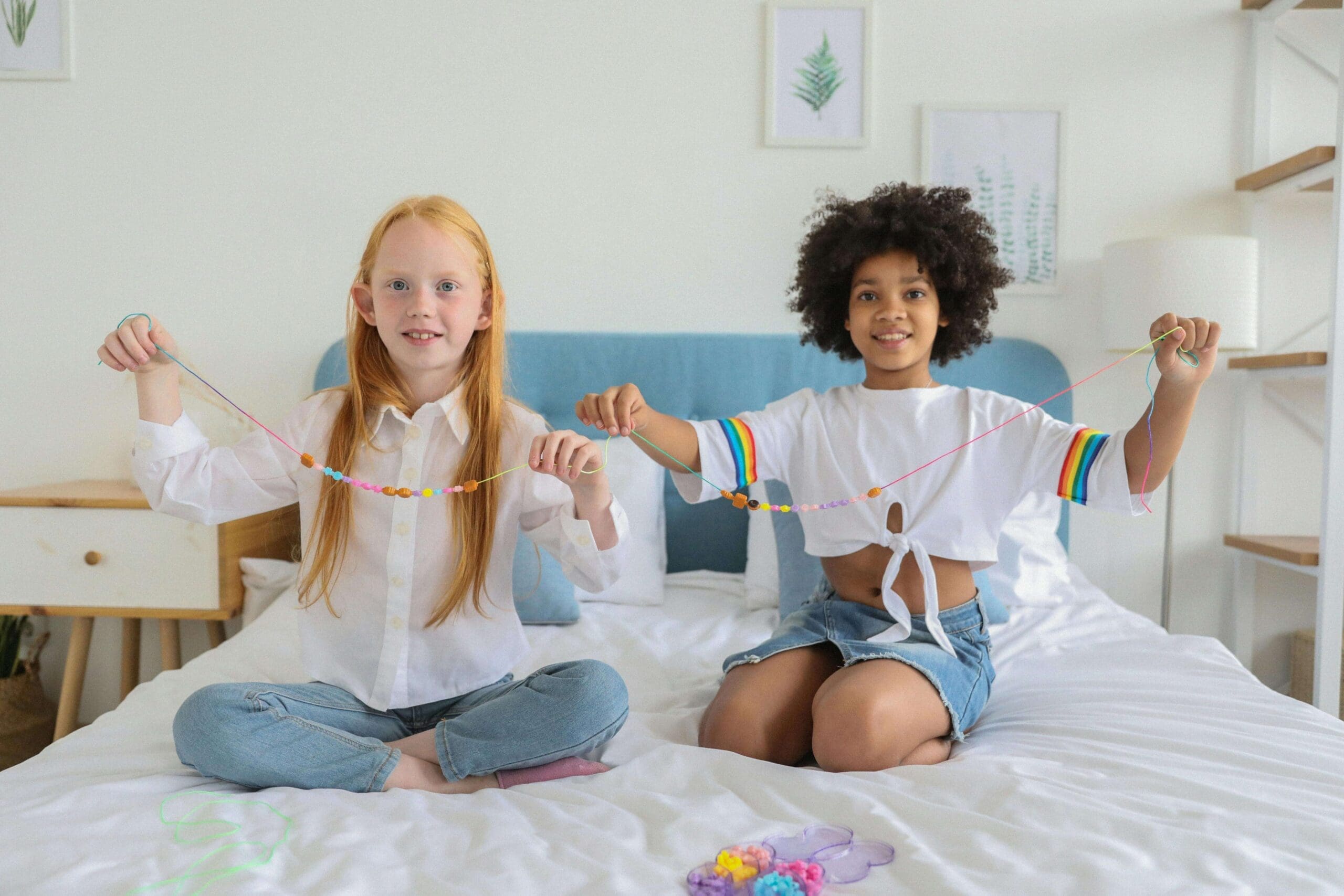 Young multiracial girls thread beads to make nacklaces