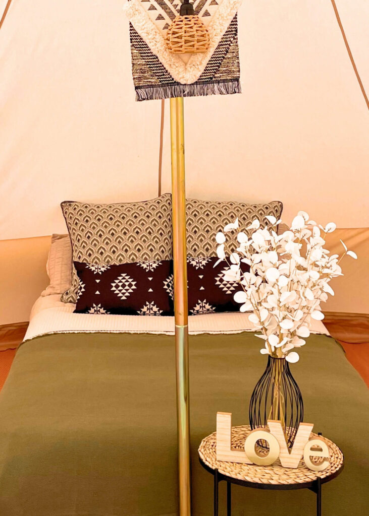 Glamping tent interior dressed in khaki green, with striking black and white contrast cushions and accessories